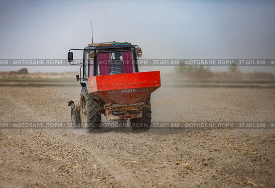 Kyzylorda Province, Kazakhstan - May 01, 2019. Tractor seeds rice in farmer's field. Spring sowing campaign. Редакционное фото, фотограф Alexey Rezvykh / Фотобанк Лори