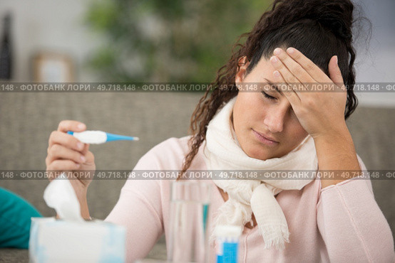 lady holding a thermometre and feeling temperature of her forehead. Стоковое фото, агентство Ingram Publishing / Фотобанк Лори