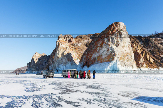 LAKE BAIKAL, OLKHON ISLAND, IRKUTSK REGION, RUSSIA -  February 22, 2025: Group of tourists listens to guide's story about Cape Sagan-Khushun - natural landmark of Olkhon Island on sunny day. Редакционное фото, фотограф Виктория Катьянова / Фотобанк Лори