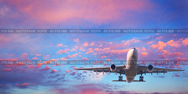 Landing airplane. Landscape with white passenger airplane is flying in the blue sky with pink clouds at sunset. Travel background. Passenger airliner. Business trip. Commercial aircraft. Private jet. Стоковое фото, агентство Ingram Publishing / Фотобанк Лори