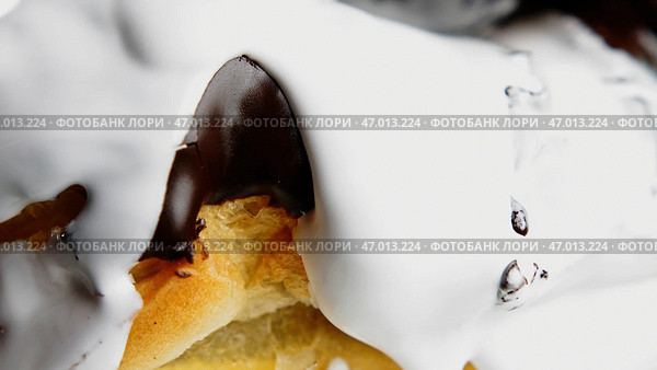 Large juicy chocolate eclairs that are poured with sugar white cream and removed close. Стоковое фото, фотограф David Kashakhi / Фотобанк Лори
