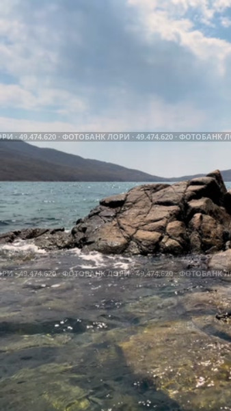 Light wave crashes against rocky shore of sea. Glistening splashes in sunshine. Стоковое видео, видеограф Кирилл Зотов / Фотобанк Лори