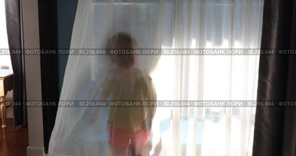 Little boy behind curtains in room. Стоковое видео, видеограф Ekaterina Demidova / Фотобанк Лори