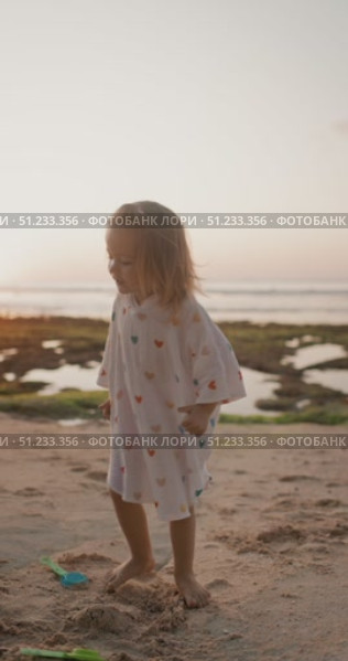 Little child girl playing on ocean sand beach with sunset tones. Стоковое видео, видеограф Wonderful nature / Фотобанк Лори