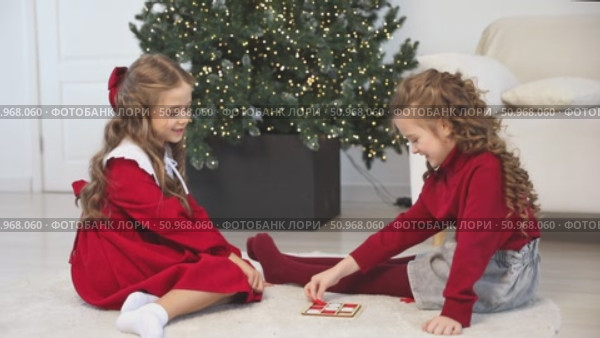 Little children girls play tic tac toe board game at home on the Christmas tree background. Children early development. Christmas and New Year holidays time. Board game and kids leisure concept. Стоковое видео, видеограф Ирина Михайличенко / Фотобанк Лори