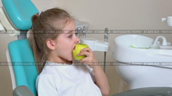 Little girl are eating green apple in the dentist's chair. Healthy teeth concept. Child eat a green apple. Slow motion footage. Стоковое видео, видеограф Ирина Михайличенко / Фотобанк Лори