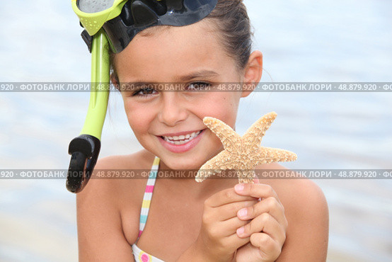 Little girl at the beach holding star fish. Стоковое фото, агентство Ingram Publishing / Фотобанк Лори