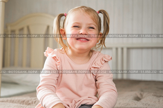 Little Girl joking sticking tongue out with silly expression. Child making face. Funny foolishness portrait of baby girl laughing in bedroom. Adorable Caucasian kid doing crazy comical gesture at home. Стоковое фото, фотограф Марина Демидюк / Фотобанк Лори