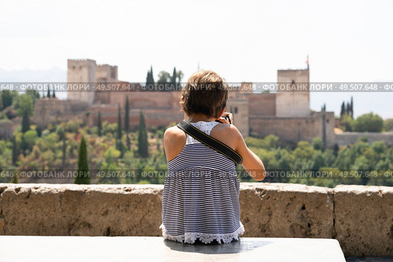 Little girl making photo with DSLR camera to the Alhambra from San Nicolas viewpoint in Albacin, Granada.. Little girl making photo with DSLR camera to the Alhambra. Стоковое фото, агентство Ingram Publishing / Фотобанк Лори