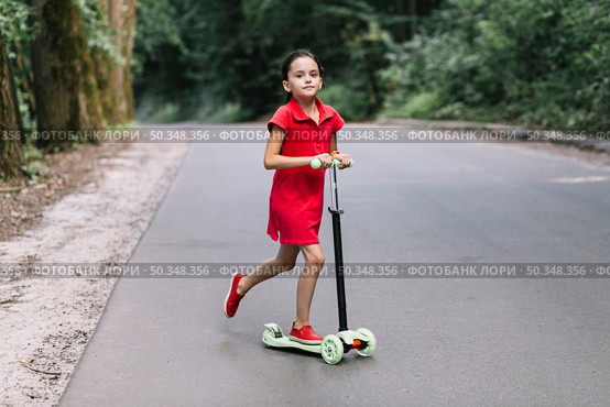 little girl riding push scooter road. Стоковое фото, агентство Ingram Publishing / Фотобанк Лори