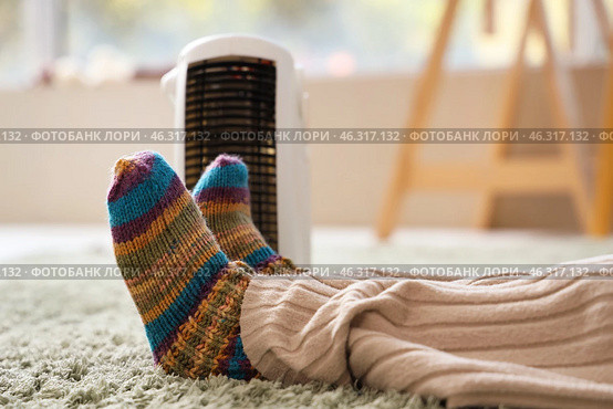 Little girl warming legs near electric heater in bedroom, closeup. Стоковое фото, фотограф Pixel_shot / Фотобанк Лори