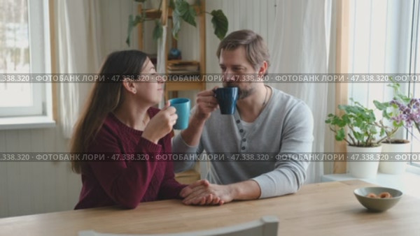 Loving mature couple interactions at home. Husband and wife hugging, holding hands and drinking morning coffee together. Man and woman talk about plans for weekend. Natural lighting. Intimate moments. Стоковое видео, видеограф Марина Демидюк / Фотобанк Лори