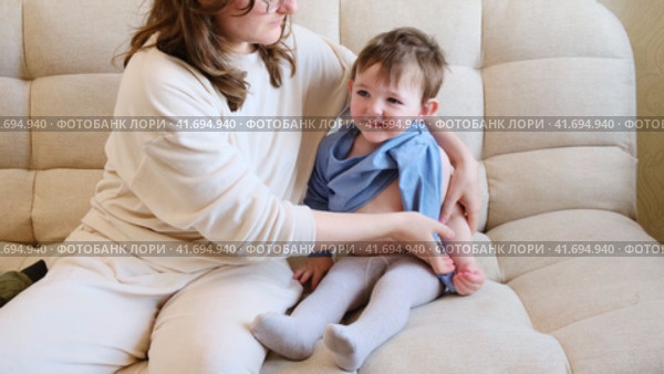 Loving mom selects warm clothes to keep her baby cozy during the walk. Mother provides child with stylish, practical outfits that will keep him warm. Kid aged about two years (one year ten months). Стоковое видео, видеограф Андрей Журавлев / Фотобанк Лори
