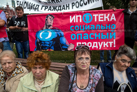 Люди держат плакат "Ипотека социально опасный продукт!" на акции протеста против социально-экономической политики Правительства РФ на площади Революции города Москвы , Россия (2015 год). Редакционное фото, фотограф Николай Винокуров / Фотобанк Лори