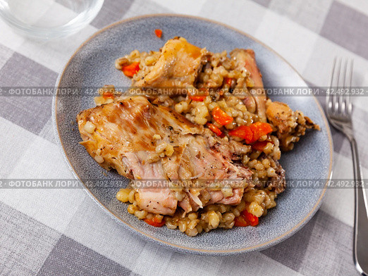 Lunch is served on plate - baked pieces of young rabbit and pearl barley. Стоковое фото, фотограф Яков Филимонов / Фотобанк Лори