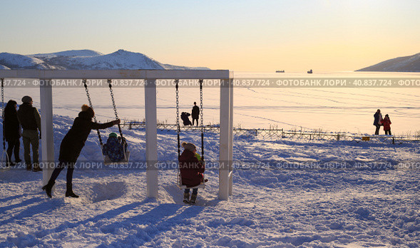 Magadan, Russia. Swing on the sea coast. Family holiday. People admire the beautiful sea view. Children have fun on the swings. Good mood. Nagaev Bay, Magadan, Siberia, Russia. Редакционное фото, фотограф Андрей Степанов / Фотобанк Лори