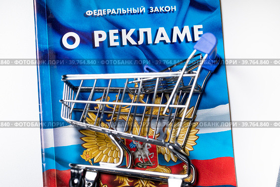 Магазинная тележка и брошюра с Федеральным законом РФ "О рекламе" на белом фоне. Стоковое фото, фотограф Николай Винокуров / Фотобанк Лори