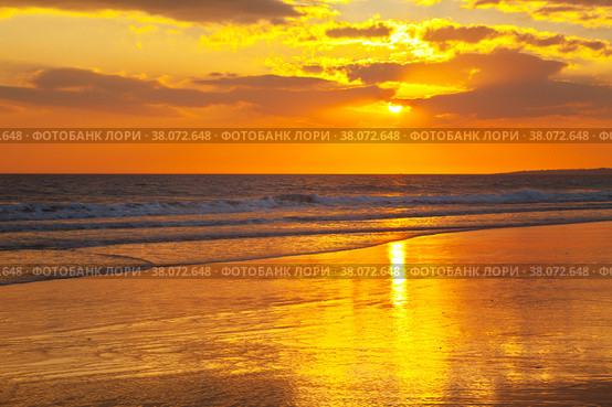 Magnificent southern sunset on the sea. The rays of the setting sun are reflected in the wet sand of a shallow beach. The rich colors of the end of a hot day on the shores of the Atlantic Ocean. Vilamoura, Falesia, Algarve, Portugal. Стоковое фото, фотограф Виктория Катьянова / Фотобанк Лори