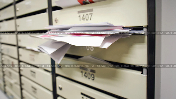 Mailboxes filled with letters and bills in an apartment building. An overflowing postbox in the hallway of the house. Стоковое фото, фотограф Андрей Журавлев / Фотобанк Лори
