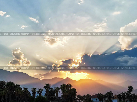Majestic sunset over mountains with dramatic clouds and rays of sunlight illuminating landscape. Стоковое фото, фотограф Наталья Семкина / Фотобанк Лори