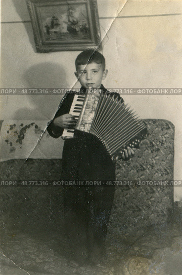 Мальчик на диване с аккордеоном в руках, 1950-е гг. Стоковое фото, фотограф Retro / Фотобанк Лори