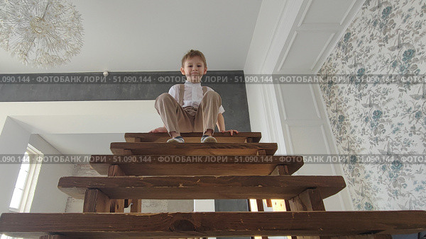 Мальчик на высокой лестнице с деревянными ступенями. A boy on a high staircase with wooden steps. Стоковое фото, фотограф Денис Баданин / Фотобанк Лори