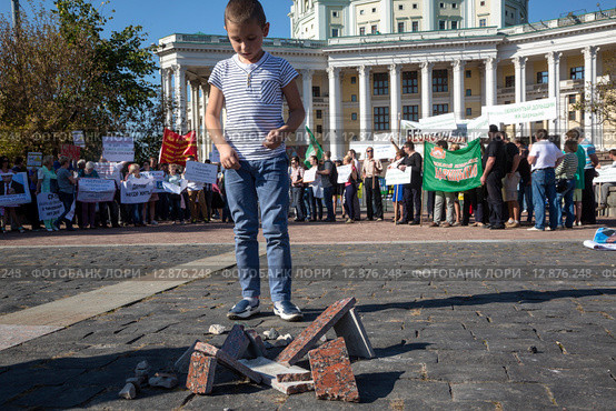 Мальчик строит дома из облицовочной гранитной плитки во время митинга обманутых дольщиков строительной компании СУ-155 на Суворовской площади города Москвы, Россия, 26 сентября 2015. Редакционное фото, фотограф Николай Винокуров / Фотобанк Лори