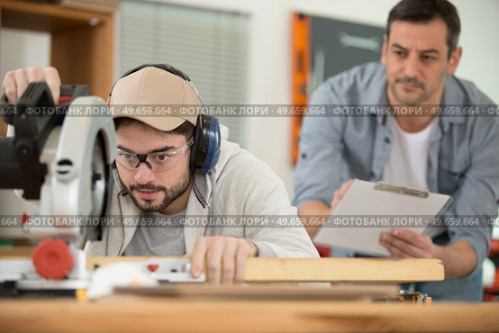 male apprentice using circular saw under supervision. Стоковое фото, агентство Ingram Publishing / Фотобанк Лори