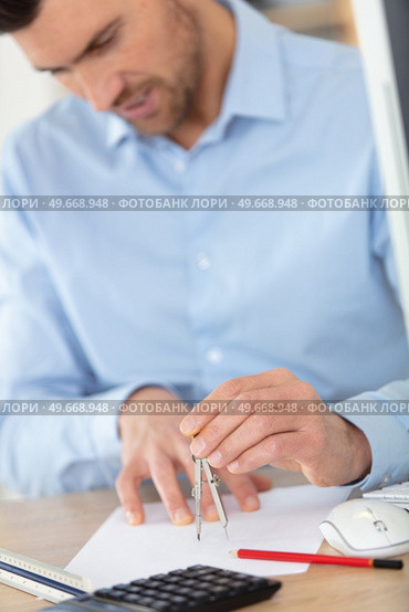 male architect in office uses a compass. Стоковое фото, агентство Ingram Publishing / Фотобанк Лори