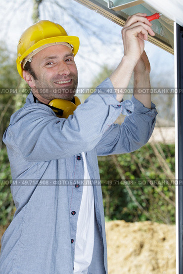 male builder in overalls assembles a window. Стоковое фото, агентство Ingram Publishing / Фотобанк Лори