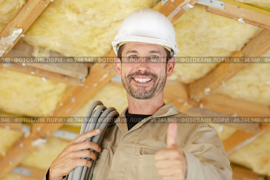 male construction worker with rale of cable trunking on shoulder. Стоковое фото, агентство Ingram Publishing / Фотобанк Лори