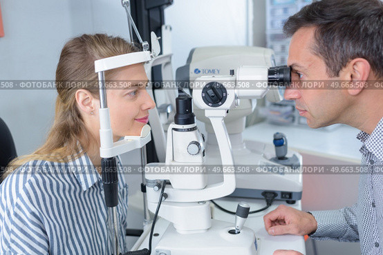 male optometrist with trial frame checking female patient vision. Стоковое фото, агентство Ingram Publishing / Фотобанк Лори