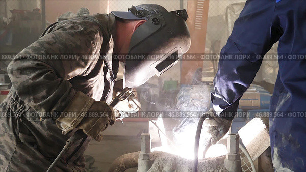 Male person in protective mask welding metall construction, concept of manufactory. Стоковое фото, фотограф David Kashakhi / Фотобанк Лори