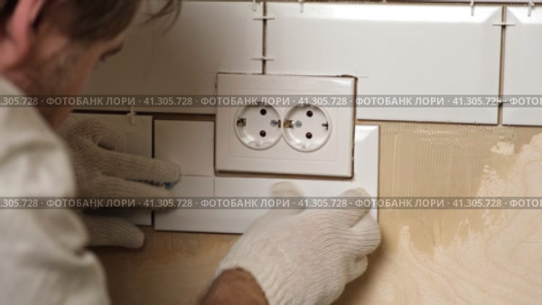 Male Worker Master Laying Ceramic Tiles on the Wall of Kitchen. Repairman Placing White Modern Tiles, Spreading Adhesive. Builder Installing Tile at Repair Renovation Work. Professional Tiling. 4K. Стоковое видео, видеограф Марина Демидюк / Фотобанк Лори