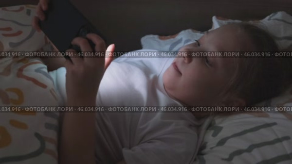 Маленькая девочка играет в мобильные игры на телефоне. Пристрастие к онлайн-видеоиграм на смартфоне. Концепция детской зависимости от технологий. Стоковое видео, видеограф Терехова Марина / Фотобанк Лори