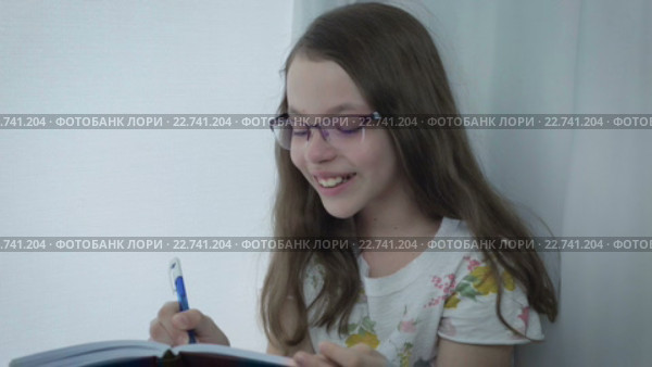 Маленькая девочка в очках пишет в дневник и смеется. Стоковое видео, видеограф Юлия Машкова / Фотобанк Лори