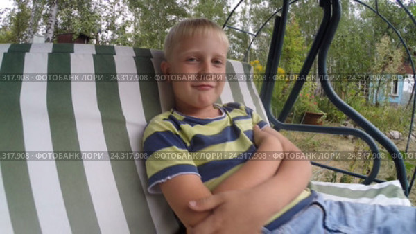Маленький светловолосый мальчик ( 7 лет ) рассуждает, качаясь на дачных качелях на природе. Стоковое видео, видеограф Mikhail Erguine / Фотобанк Лори
