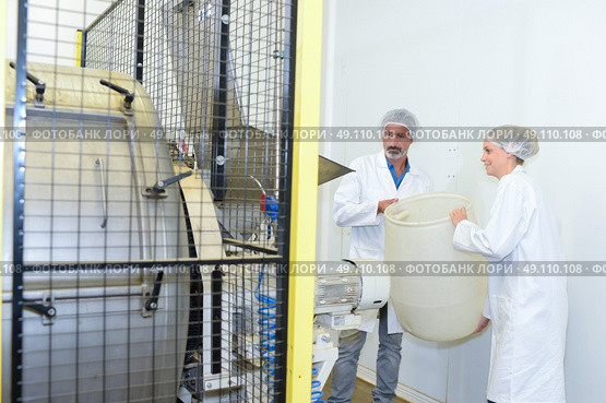 Man and woman holding plastic barrel next to machine. Стоковое фото, агентство Ingram Publishing / Фотобанк Лори