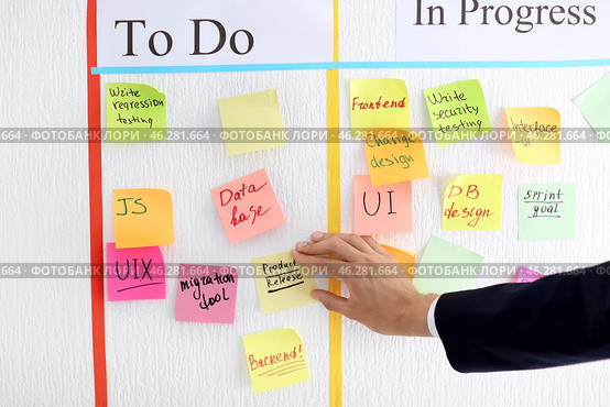 Man attaching sticky note to scrum task board in office. Стоковое фото, фотограф Pixel_shot / Фотобанк Лори