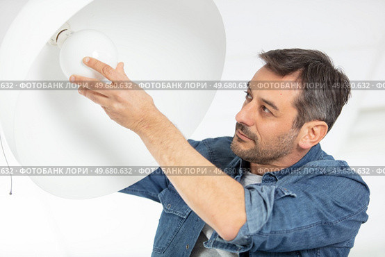 man changing light bulb in pendant lamp indoors. Стоковое фото, агентство Ingram Publishing / Фотобанк Лори