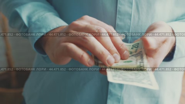 Man counts cash in a cozy room while managing personal finances in the afternoon light. Стоковое видео, видеограф Сергей Толмачёв / Фотобанк Лори