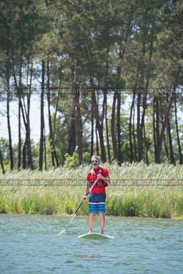 man enjoying a ride on the lake with paddleboard. Стоковое фото, агентство Ingram Publishing / Фотобанк Лори