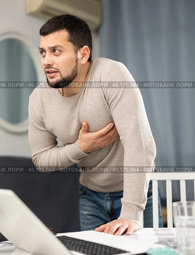 Man experiencing chest pain after working long hours on laptop. Стоковое фото, фотограф Яков Филимонов / Фотобанк Лори