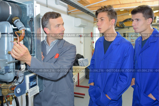 Man explaining workings of boiler to two trainees. Стоковое фото, агентство Ingram Publishing / Фотобанк Лори