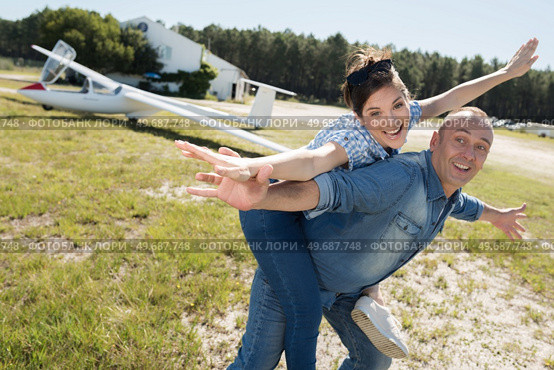 man giving his girlfriend piggyback arms outstretched like an aircraft. Стоковое фото, агентство Ingram Publishing / Фотобанк Лори