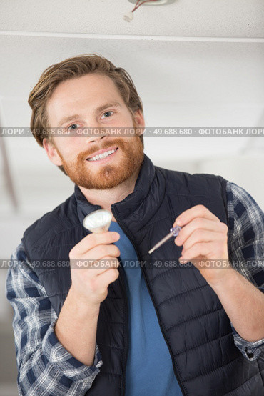 man holding a lightbulb and a screwdriver. Стоковое фото, агентство Ingram Publishing / Фотобанк Лори