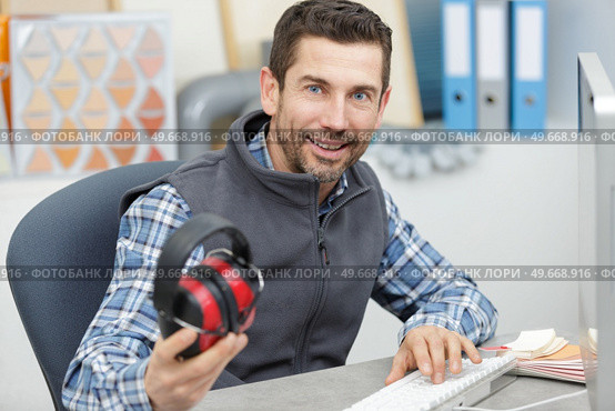 man holding earmuffs in the office. Стоковое фото, агентство Ingram Publishing / Фотобанк Лори