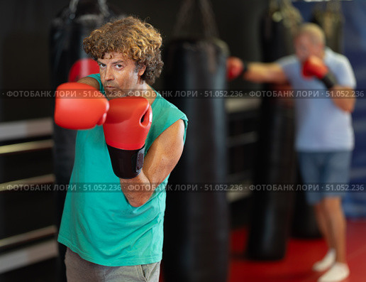 Man in red boxing gloves posing in fighting stance in gym. Стоковое фото, фотограф Яков Филимонов / Фотобанк Лори