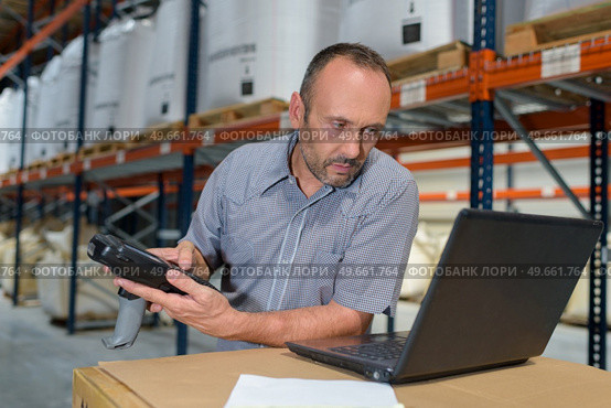 man in warehouse holding scanner and looking at laptop. Стоковое фото, агентство Ingram Publishing / Фотобанк Лори