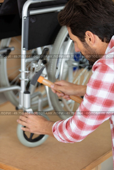 man is repairing a wheelchair at workshop. Стоковое фото, агентство Ingram Publishing / Фотобанк Лори